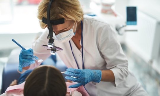 Dental patient smiling during an exam with an oral surgeon, illustrating odontoma tumor care