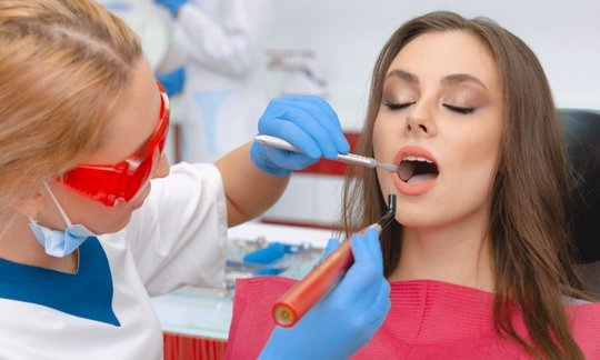 Oral surgeon using a dental laser during a precise soft-tissue procedure