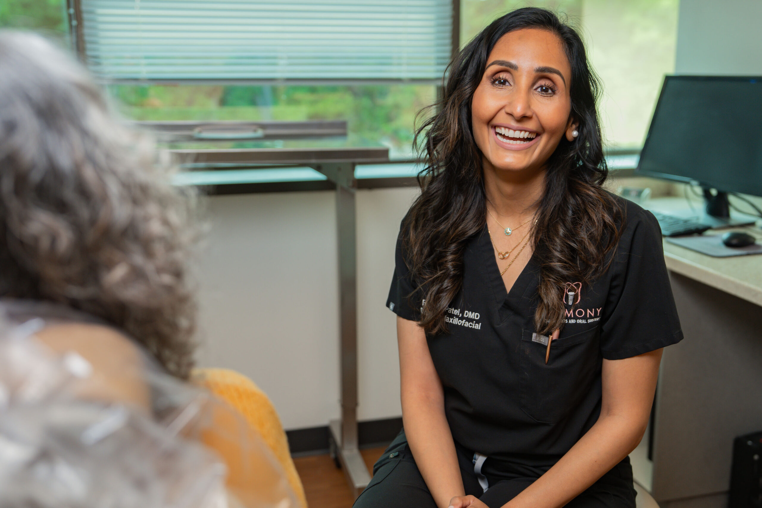 Dr. Riddhi Patel speaking with a patient at Harmony Dental Implants and Oral Surgery