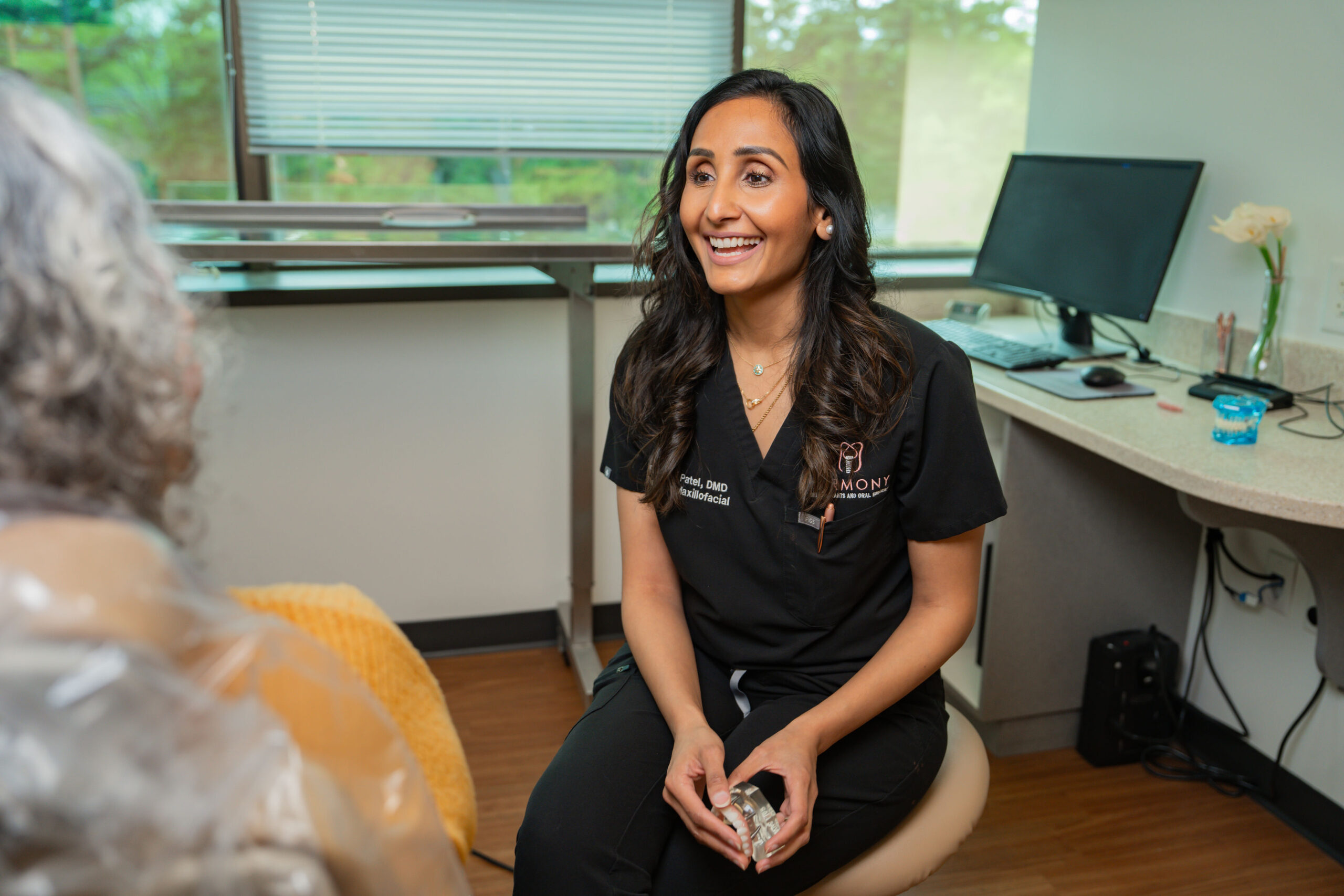 Dr. Patel showing a dental implant model to a patient at Harmony Dental Implants and Oral Surgery